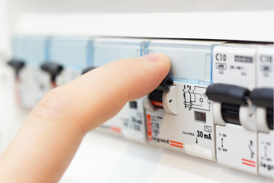 Intérieur technique avec personne actionnant un disjoncteur différentiel dans un tableau électrique résidentiel