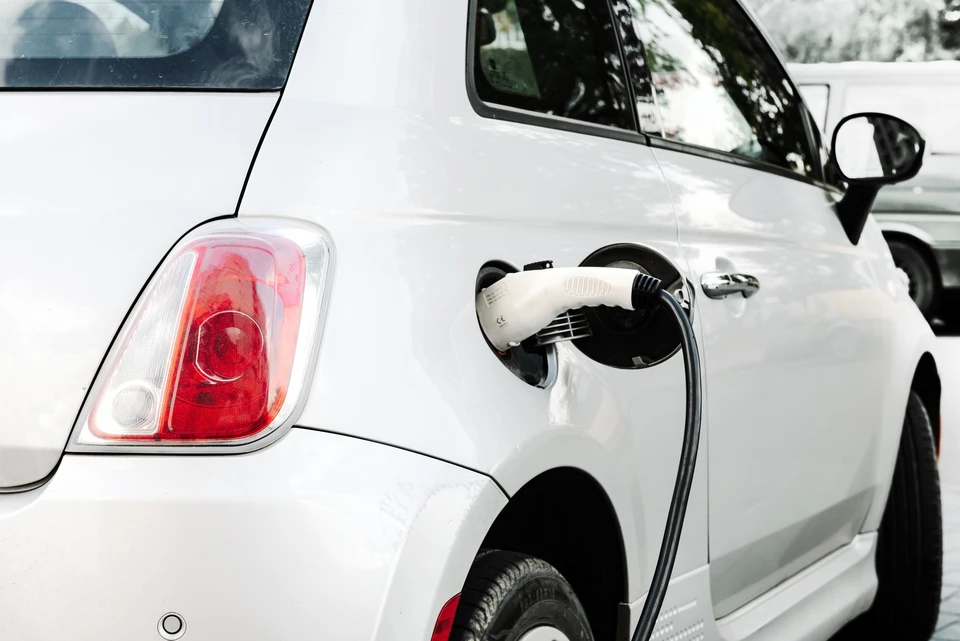 Scène extérieure montrant une voiture électrique blanche en cours de recharge
