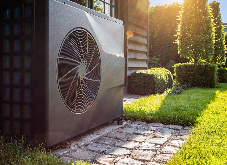 Extérieur résidentiel avec unité de climatisation/pompe à chaleur installée sur dalle en pierre naturelle
