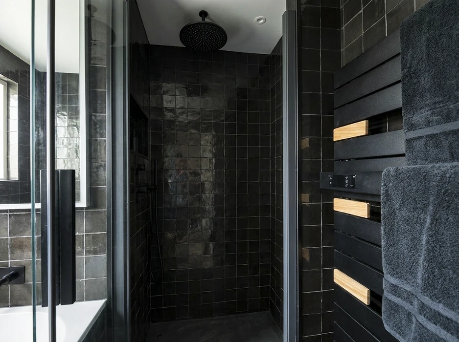Douche à l'italienne de style industriel, entièrement carrelée en zellige noir brillant, avec pommeau de douche encastré au plafond